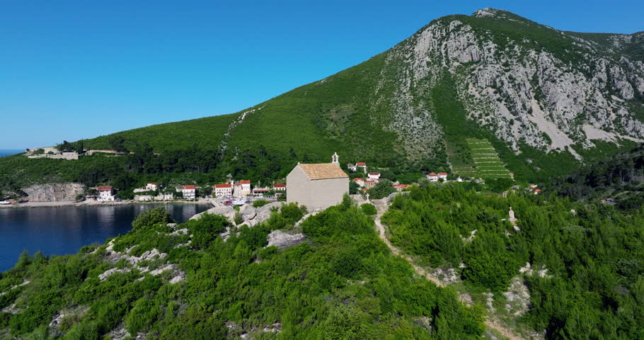 Flying By St. Michael Church, Revealing Bay With Docked Catamaran Boat And Cruise Ship. Trstenik, Peljesac Peninsula, Croatia. drone shot