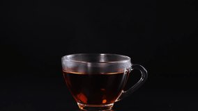 A sugar cube drops into a tea cup, creating a splash against a black background. Captured in high-speed photography - Powered by Shutterstock - Get 15% off with code: PIKWIZARD15