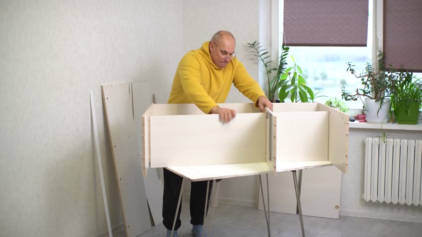 A person is assembling a basic furniture piece in a cozy room filled with plants. It's an afternoon activity, showcasing the process of putting parts together using instructions.