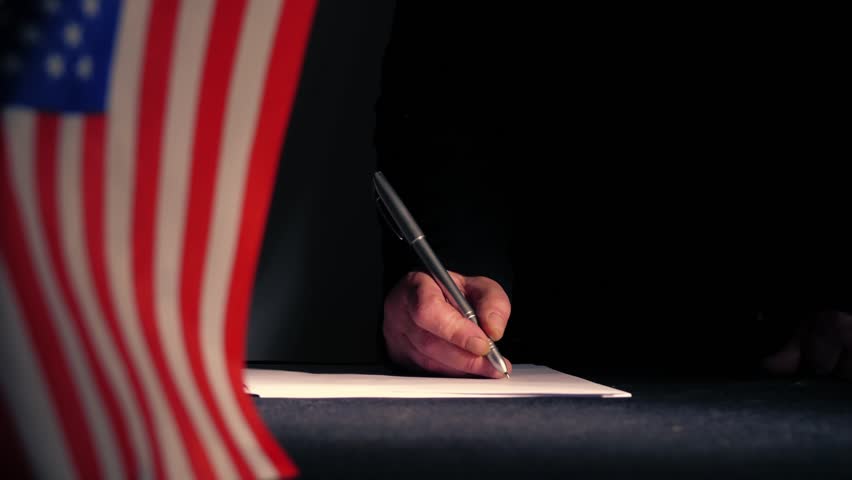 Hand signing a trade deal with American USA flag medium zoom shot selective focus