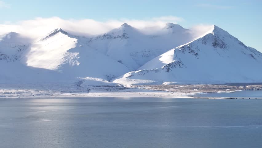 Snow blankets Hafnarfjall mountain and quiet fjord waters near Borgarnes Iceland
