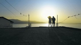 Silhouette of romantic couple standing on balcony enjoying sunset over the sea during summer vacation - Powered by Shutterstock - Get 15% off with code: PIKWIZARD15