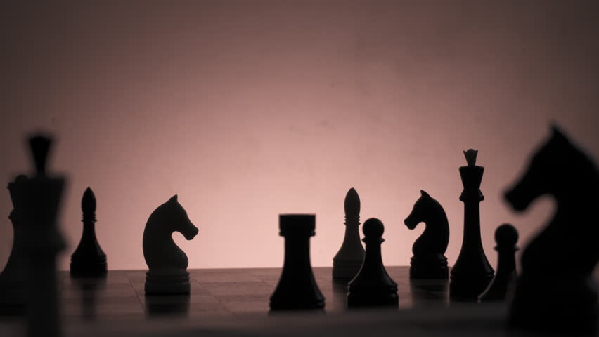 Silhouette of a man hand, over knight piece, grabbing and grind it in fury
