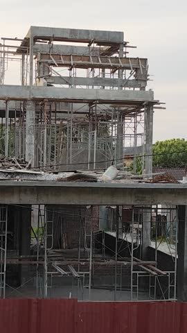 A concrete skeleton reaching for the sky, surrounded by scaffolding and the remnants of construction.