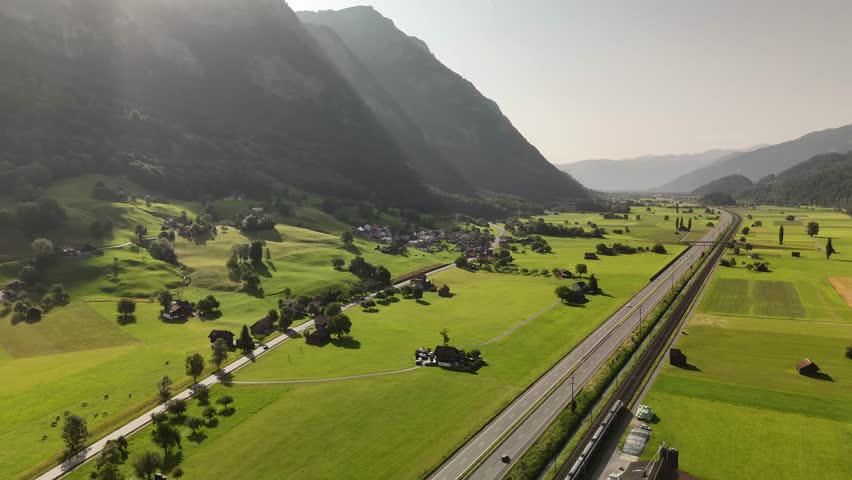 Aerial View of Walenstadt Valley in Switzerland with Lush Green Fields, Mountain Shadows and Rural Alpine Landscape