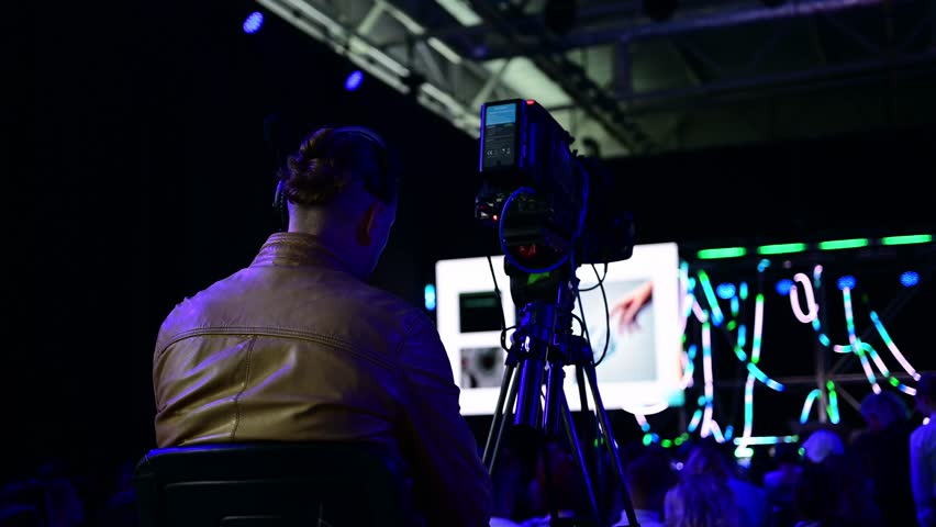 Engaged audience at innovative tech conference with keynote speaker and digital displays
