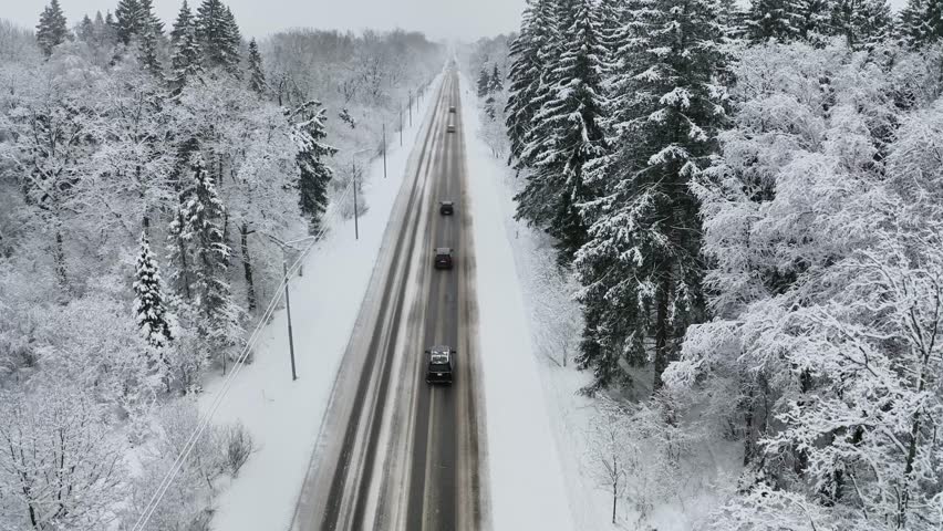 Aerial view of road with cars driving through winter forest with snow. Concept of dangerous driving on slippery and snowy road