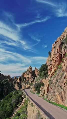 A road winding through a majestic mountain range in Corsica, France.