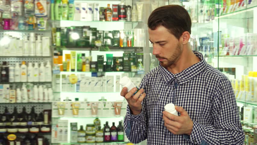 Man contemplating between two medication options in a pharmacy