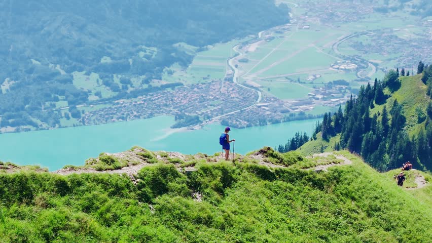 Hiker walks along the narrow Hardergrat ridge with Lake Brienz shimmering below