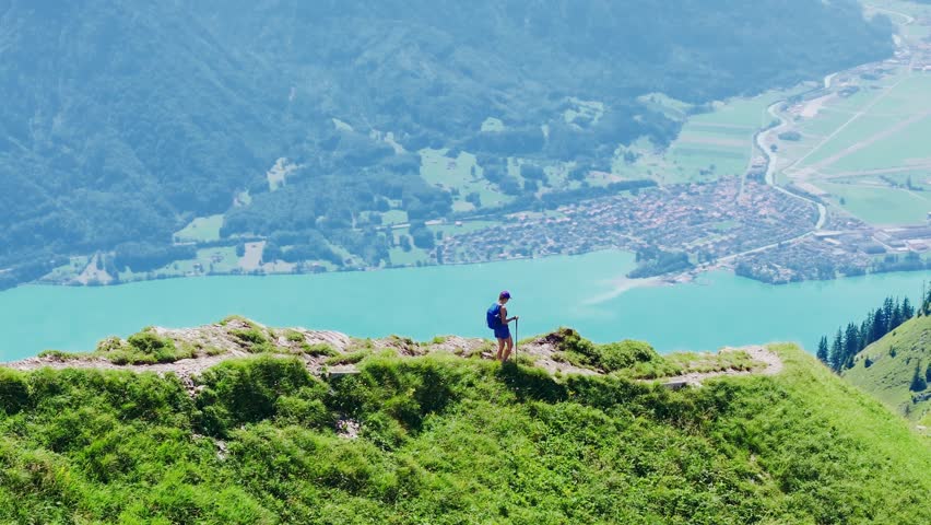 Hiker walks along the narrow Hardergrat ridge with Lake Brienz shimmering below