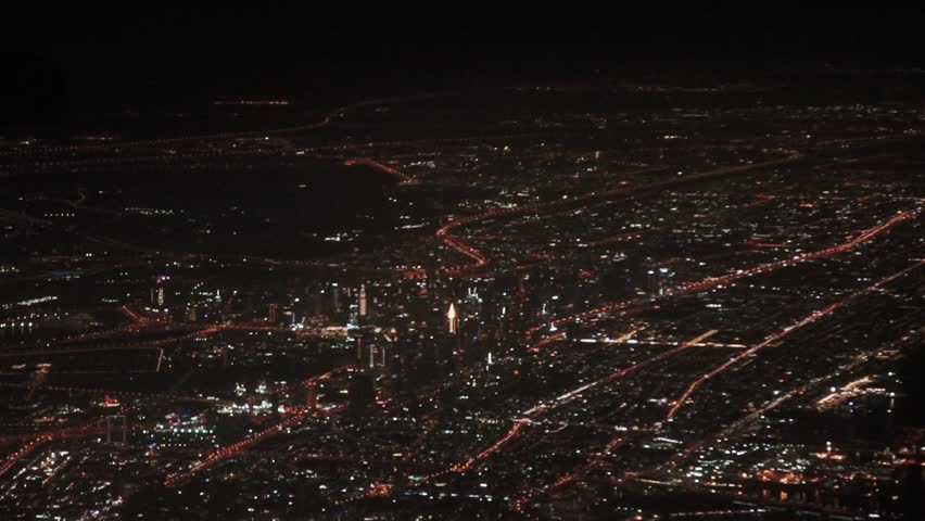 Night city Dubai in the United Arab Emirates from the window of the plane. Travel by plane in the Middle East and Arabia. Business center and technological downtown from above. Burj Khalifa