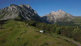 White car driving along picturesque mountain ridge in the morning through green meadows crossing idyllic alpine landscape with high mountains in the background, aerial view - Powered by Shutterstock - Get 15% off with code: PIKWIZARD15