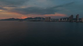 Early morning drone view from sea to coastal city. Colorful clouds at sunrise illuminate high-rise buildings forming a pattern like an equalizer along the shoreline. 4K 60FPS - Powered by Shutterstock - Get 15% off with code: PIKWIZARD15