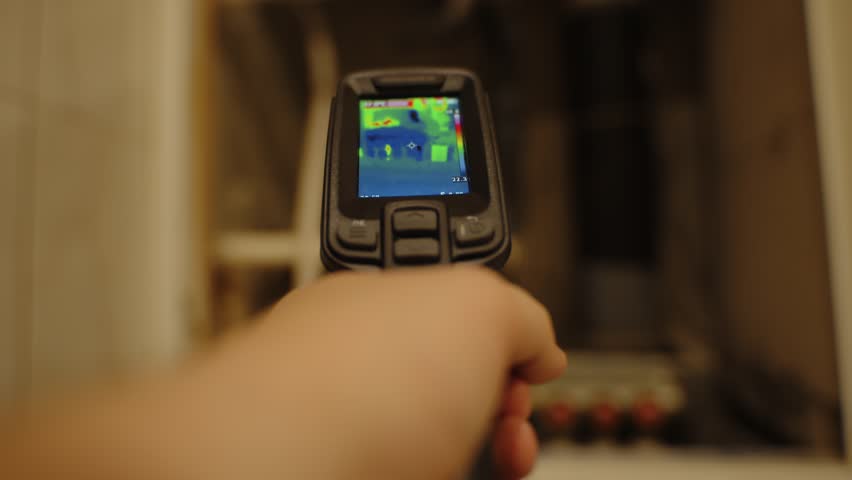 Hand using thermal imaging camera to inspect heating pipes