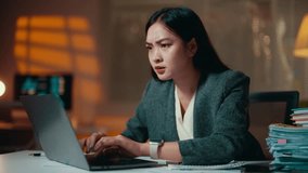 Professional female entrepreneur experiencing workplace stress, multitasking with laptop and smartwatch during late-night work session, surrounded by paperwork - Powered by Shutterstock - Get 15% off with code: PIKWIZARD15