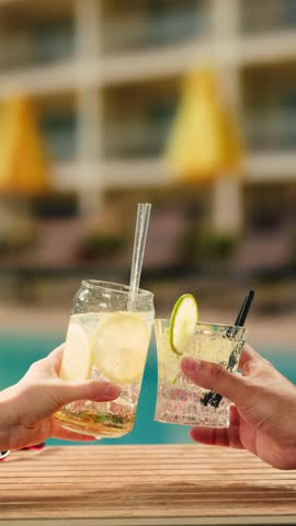 Fruit cocktail in hotel bar, Two cocktail glasses cheers in the hands on sea background. Bartenter making drink in bar, Summer vacation concept, A beautiful couple enjoy the vacation at the beach.