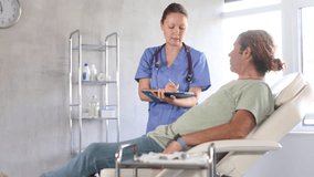 Doctor consulting patient filling form at consultation. Professional physician talking to man signing medical paper at appointment visit in clinic. Commercial medicine.  - Powered by Shutterstock - Get 15% off with code: PIKWIZARD15