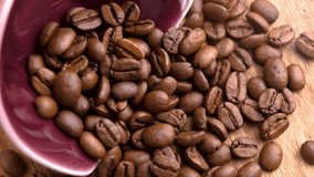 Roasted coffee beans falling in slow motion on pile of scattered Arabica grains from red bowl on wooden table - Powered by Shutterstock - Get 15% off with code: PIKWIZARD15