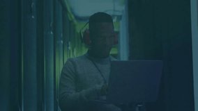 Data center technician typing on laptop at racks causing red circuits pulsing and signaling breach. Technology, cybersecurity, digital, industrial, innovation, data, network - Powered by Shutterstock - Get 15% off with code: PIKWIZARD15