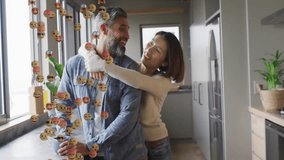 Couple embracing in kitchen with coffee mug initiating emojis rising around couple for social media. Affection, intimacy, warmth, companionship, vibrancy, modernity, casual - Powered by Shutterstock - Get 15% off with code: PIKWIZARD15