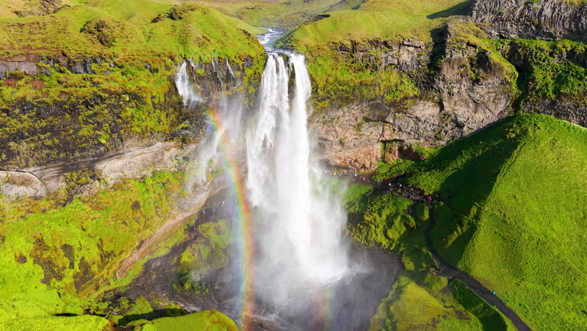 Seljalandsfoss Waterfall in Iceland, highlighted by a beautiful rainbow
