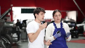 European guy consults with a car service worker about the repair and diagnostics of the car. Female mechanic gives recommendations for changing the oil, filter and checking the engine. High quality 4k - Powered by Shutterstock - Get 15% off with code: PIKWIZARD15