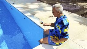 Mature man relaxing by the pool, enjoying a rose wine on a sunny day - Powered by Shutterstock - Get 15% off with code: PIKWIZARD15