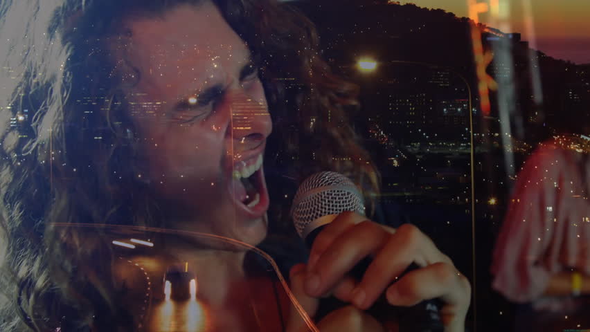Male singer holding microphone performing music with city-night overlay flickering across face. Performance, musician, entertainment, nighttime, stage, emotion, vocals