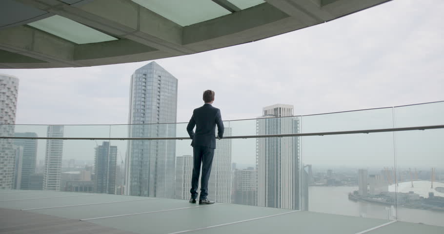 Businessman in Suit Walking on Office Rooftop Looking out over City Skyline