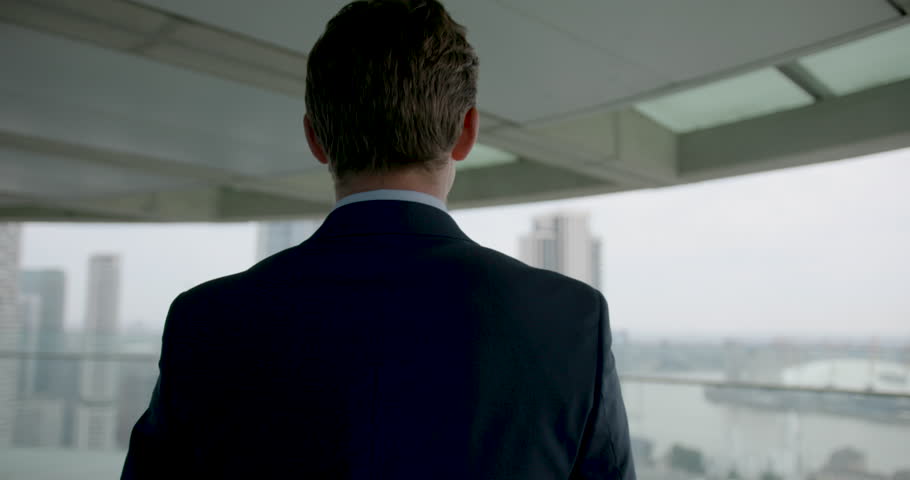 Businessman in Suit Walking on Office Rooftop Looking out over City Skyline
