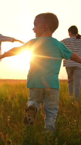 Mother daughter son running through meadow dreaming about flying to sky slow motion. Mom children having fun with raised hands dreaming in nature park. Family superhero game. Happy family silhouette