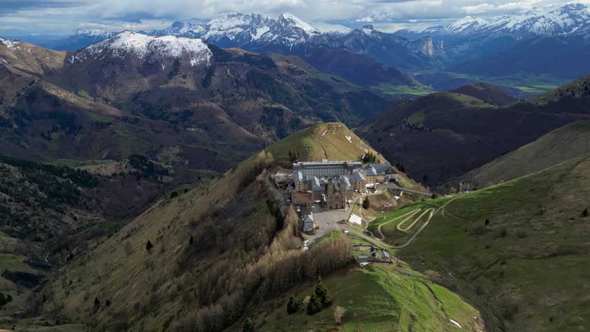 Panoramic view of the Basilica of Our Lady of La Salette in the French Alps, surrounded by lush forests and snow-covered mountains. Site of the 1846 Marian apparitions.