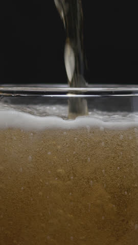 Beer pouring and splashing in super slow motion with visible foam and bubbles. Close-up macro shot capturing refreshing texture and movement, perfect for beverage commercials or drink promos.