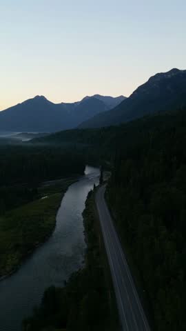 Majestic Mountains and Winding Road Alongside a Serene River in British Columbia, Canada.