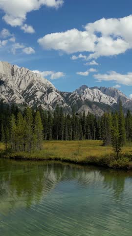 Majestic Canadian Rocky Mountains And Pine Forest Reflected In A Tranquil Lake Under Blue Sky.