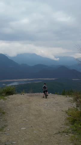 Adventurous Mountain Biker Pauses To Appreciate Panoramic Views Of Canadian Wilderness Landscape