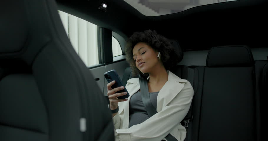 Woman Getting in Self driving car and using smartphone in back of taxi in city