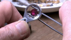 A jeweler carefully examines a red gemstone or Ruby through a magnifying loupe, checking for clarity and quality. The process highlights the precision and skill involved in gem appraisal. - Powered by Shutterstock - Get 15% off with code: PIKWIZARD15