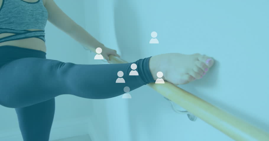 Standing barefoot on wood floor by barre, woman shifting weight and lifting leg for fitness stretch. Fitness, flexibility, ballet, stretching, exercise, wellness, dance