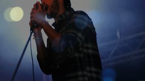 Backlight flaring revealing male singer gripping mic on music stage singing and energizing audience. Performance, stage, vocalist, microphone, entertainment, concert, spotlight - Powered by Shutterstock - Get 15% off with code: PIKWIZARD15