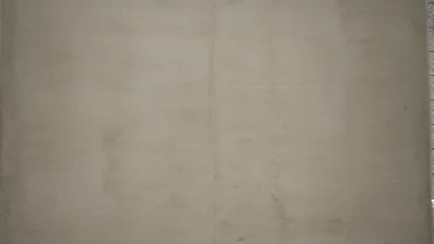 Side tracking of confident female model walking through modern subway station hall. Sexy woman walks seductively wearing black high heeled boots and long coat. Futuristic architecture concrete walls