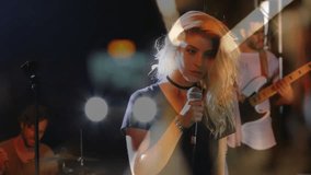 Low-angle shot panning revealing female vocalist gripping mic performing music under stage lights. Performance, concert, entertainment, stage, musicians, live, energy - Powered by Shutterstock - Get 15% off with code: PIKWIZARD15