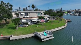 American flag on private jetty of apartment Building at John Pass River in Florida. Surfboard in garden and tropical Palm trees. Aerial backwards wide shot. Proud family in Madeira Beach. - Powered by Shutterstock - Get 15% off with code: PIKWIZARD15