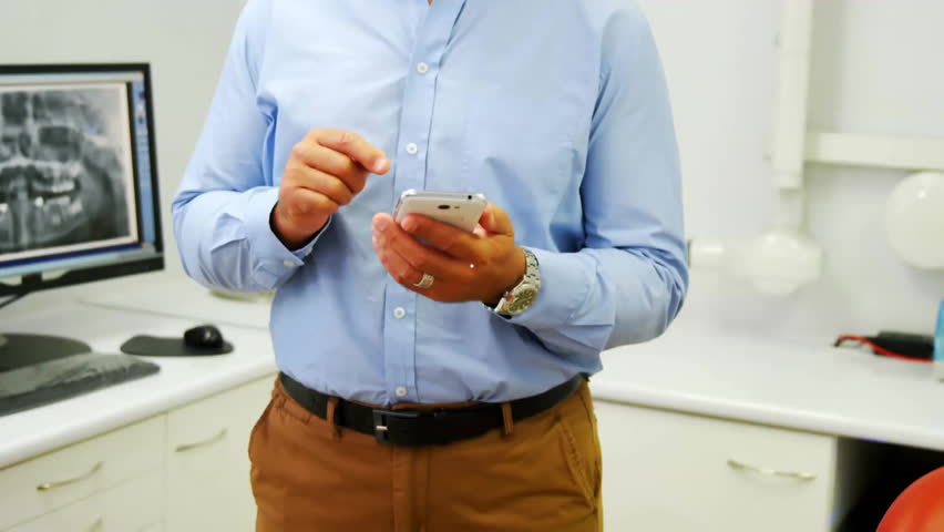 Dentist tapping phone and activating holographic clock displaying timing data with cyan lines. Technology, augmented reality, digital interface, healthcare, innovation, futuristic, data visualization - Powered by Shutterstock - Get 15% off with code: PIKWIZARD15