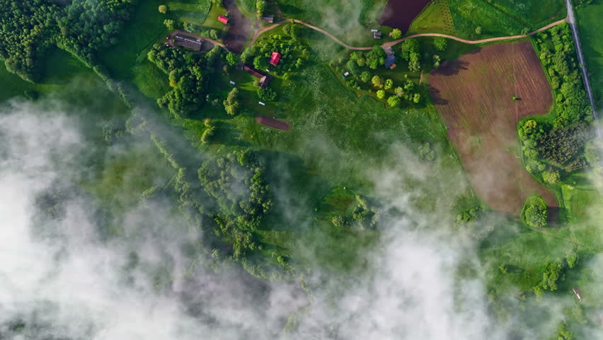 Green countryside with farmsteads of Latvia and clouds, aerial top down
