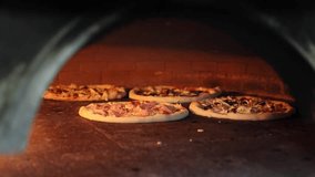 4k pizza wood oven video. Pizzas baking inside a hot wood-fired oven. Open flames and rustic interior highlight traditional artisan cooking methods. Italian wooden fire artigianale pizza. - Powered by Shutterstock - Get 15% off with code: PIKWIZARD15