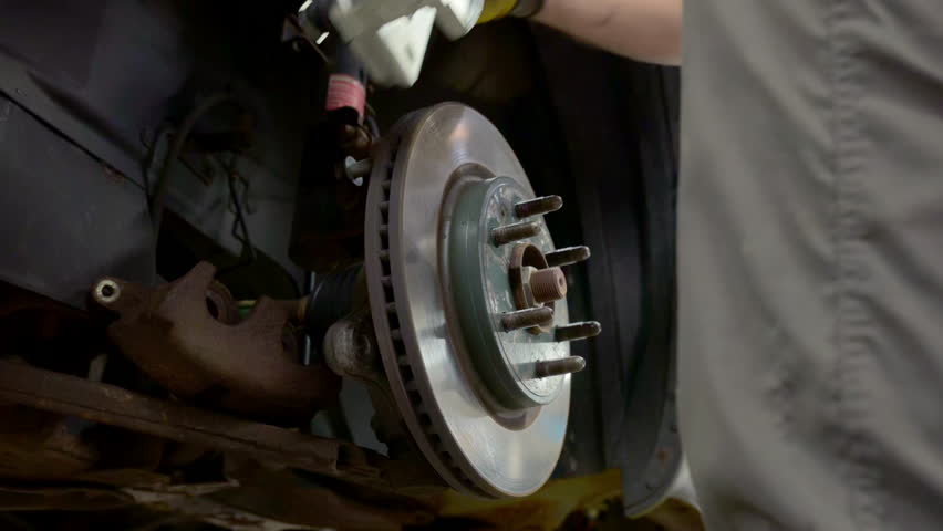 Auto mechanic installing new brakes with his tool on a modern vehicle. Close up shot 