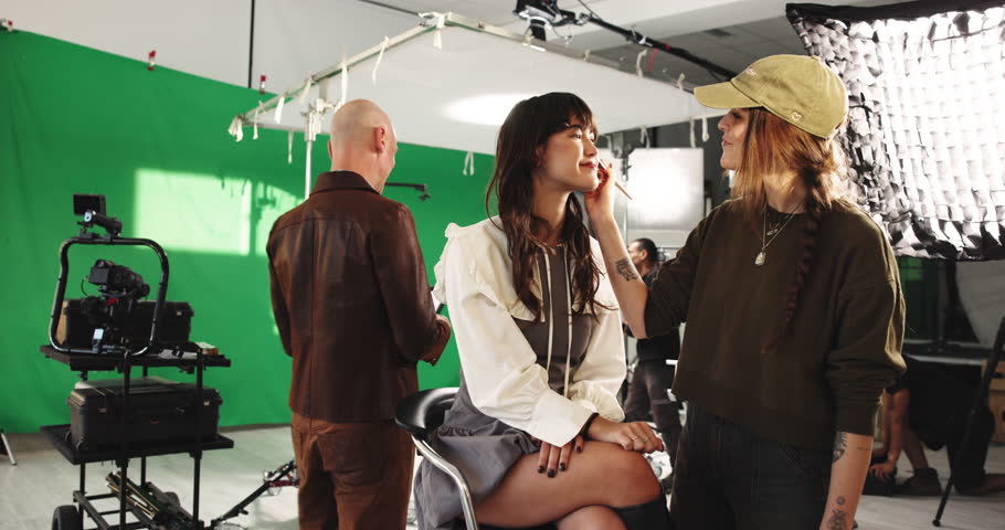 High five, makeup and styling with director on set for production or videography success. Behind the scenes, green screen and thumbs up with man speaking to talent in studio for film satisfaction