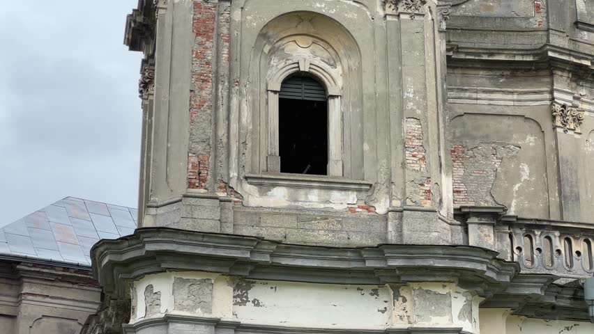 One of the tiers of the main facade Baroque masonry Church of Immaculate Conception of the 18th century in Horodenka, Ukraine, view close-up while panning in overcast rainy day 
